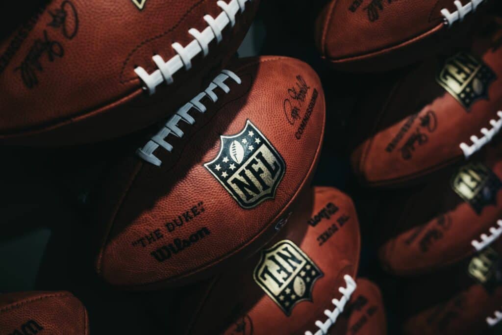 Pile of Wilson "The Duke" leather American footballs bearing the NFL shield logo