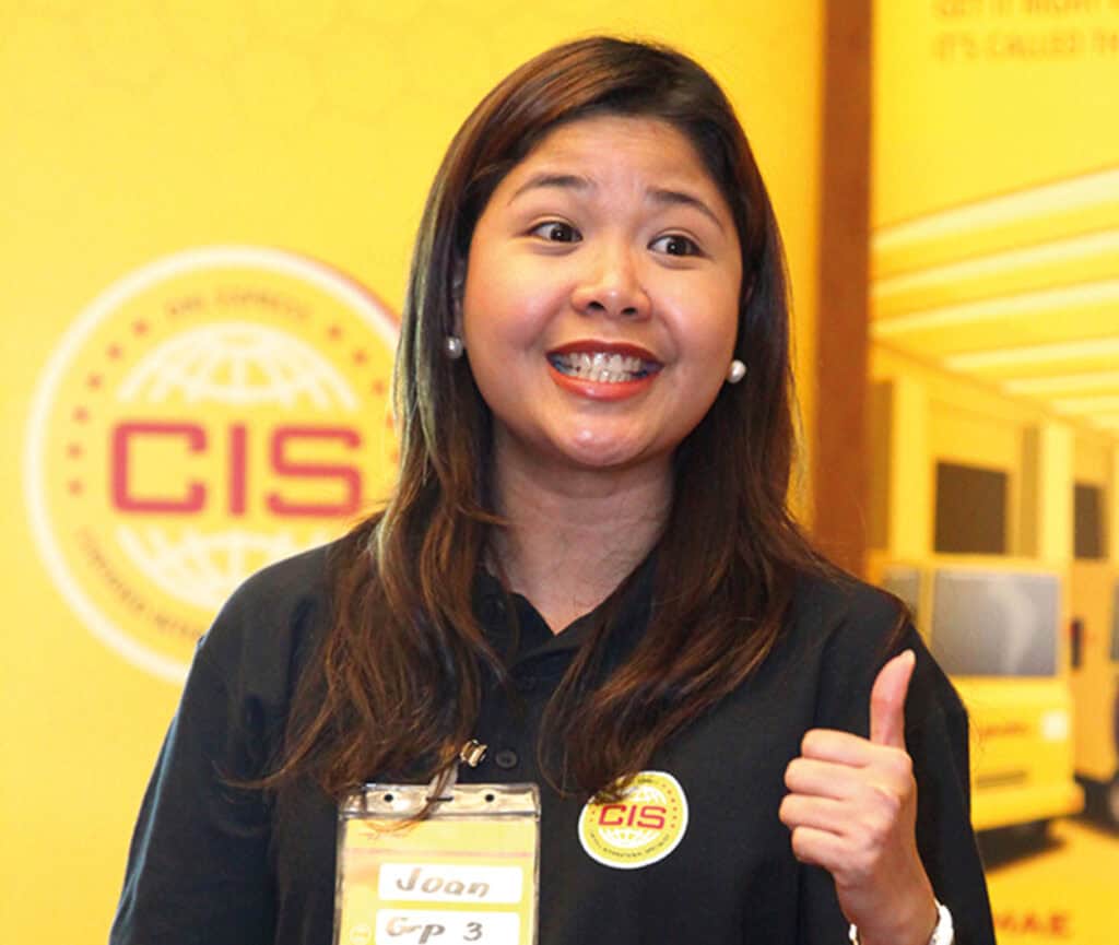 Delegate named Joan giving a thumbs up in front of a yellow CIS branded backdrop