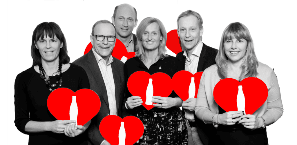 Six colleagues in black and white holding red hearts printed with the Coca-Cola bottle shape