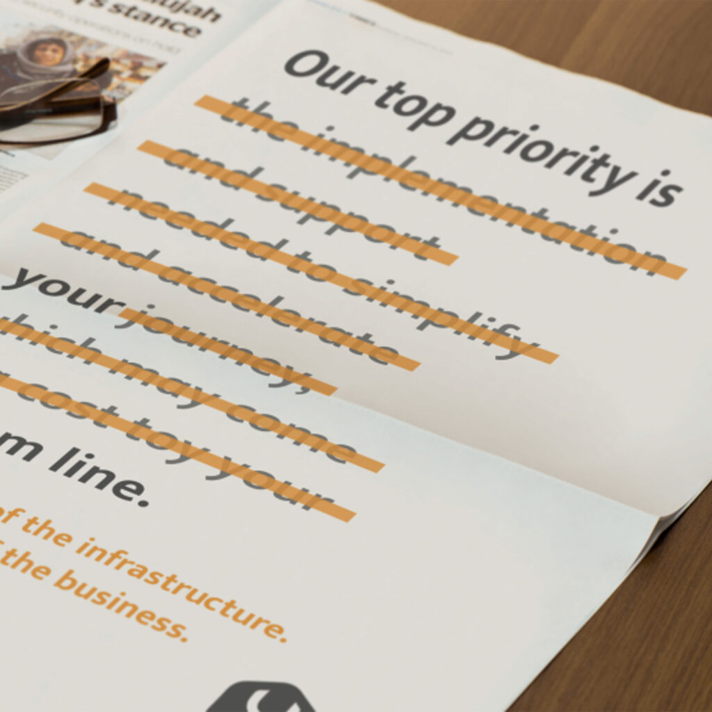 A CloudHelix press advert open on a desk beside a newspaper and reading glasses, its copy struck through in orange.
