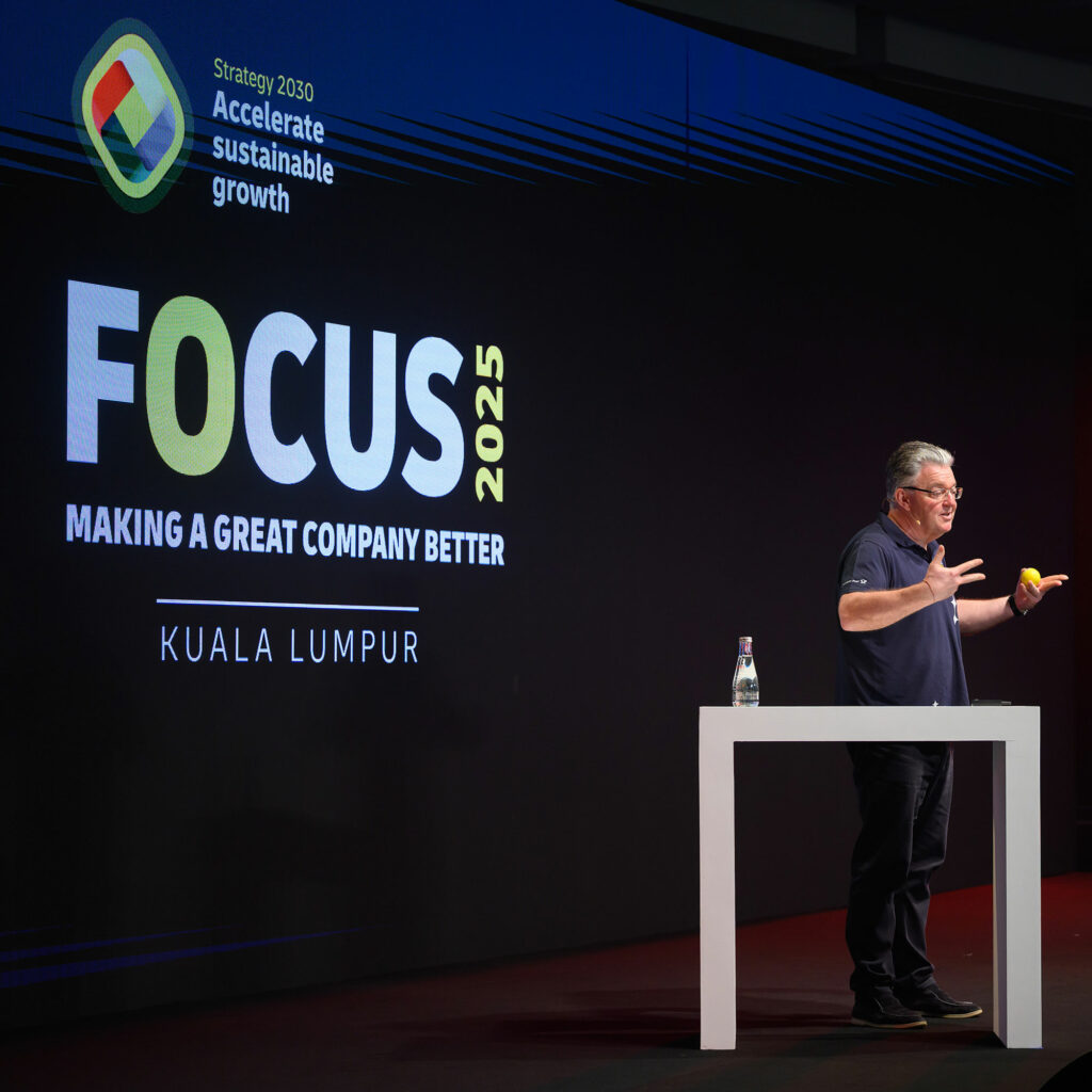 A speaker on stage beside the FOCUS 2025 title graphic, reading "Making a great company better" above "Kuala Lumpur".
