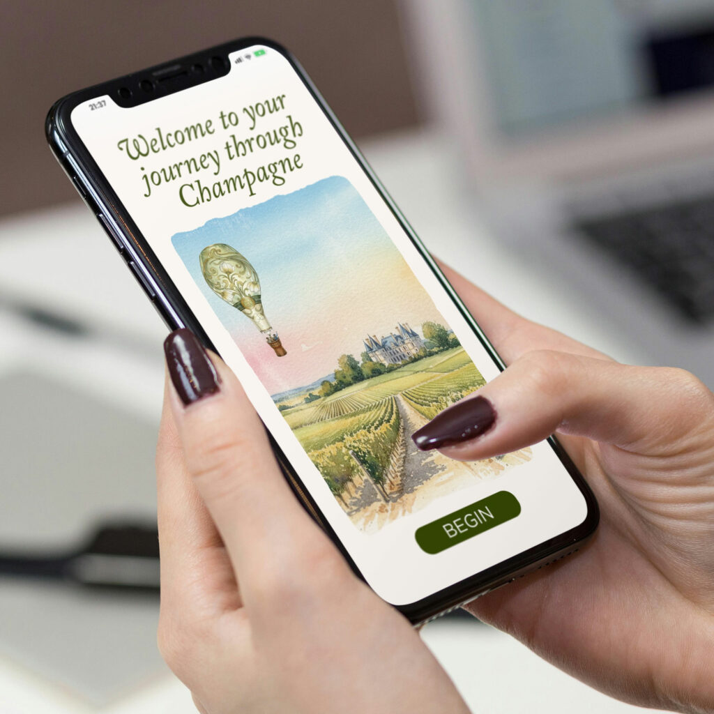 A phone held in one hand showing the opening screen of the Journey through Champagne module, with a watercolour hot air balloon over a chateau and vineyards, and a Begin button.