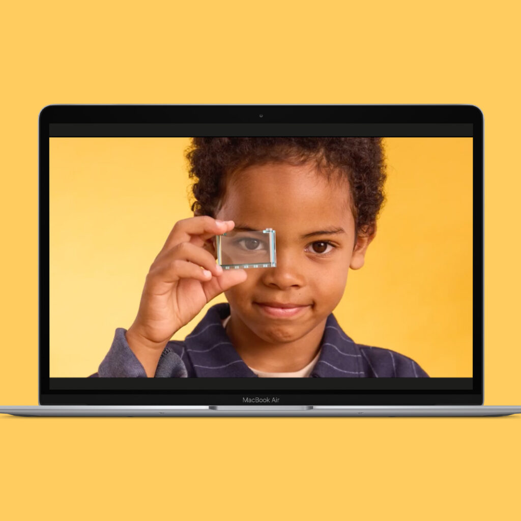 The Mass Balance film playing on a laptop, showing a child holding a transparent LEGO element to their eye